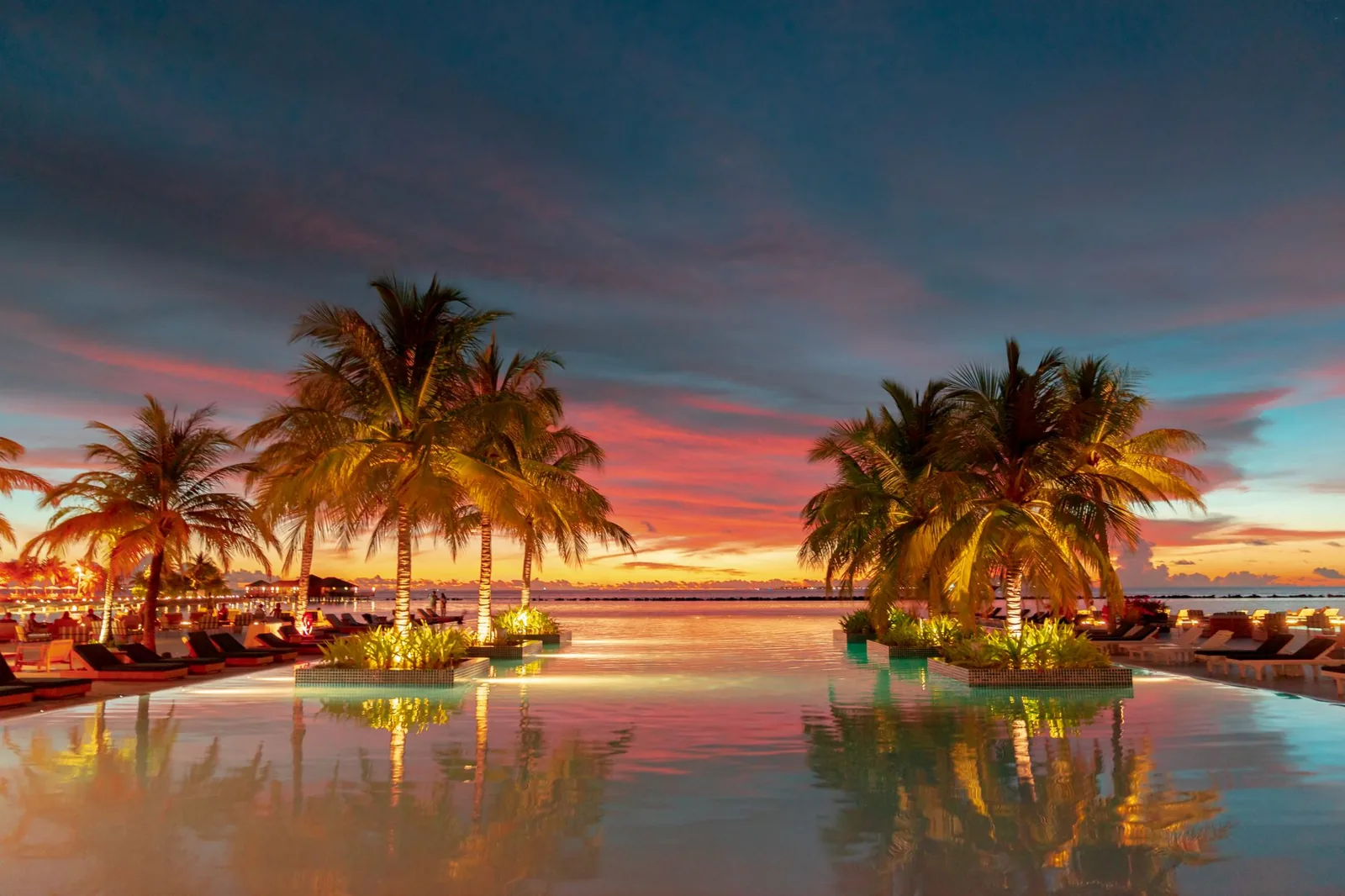 Couple relaxing at an all-inclusive resort pool at sunset